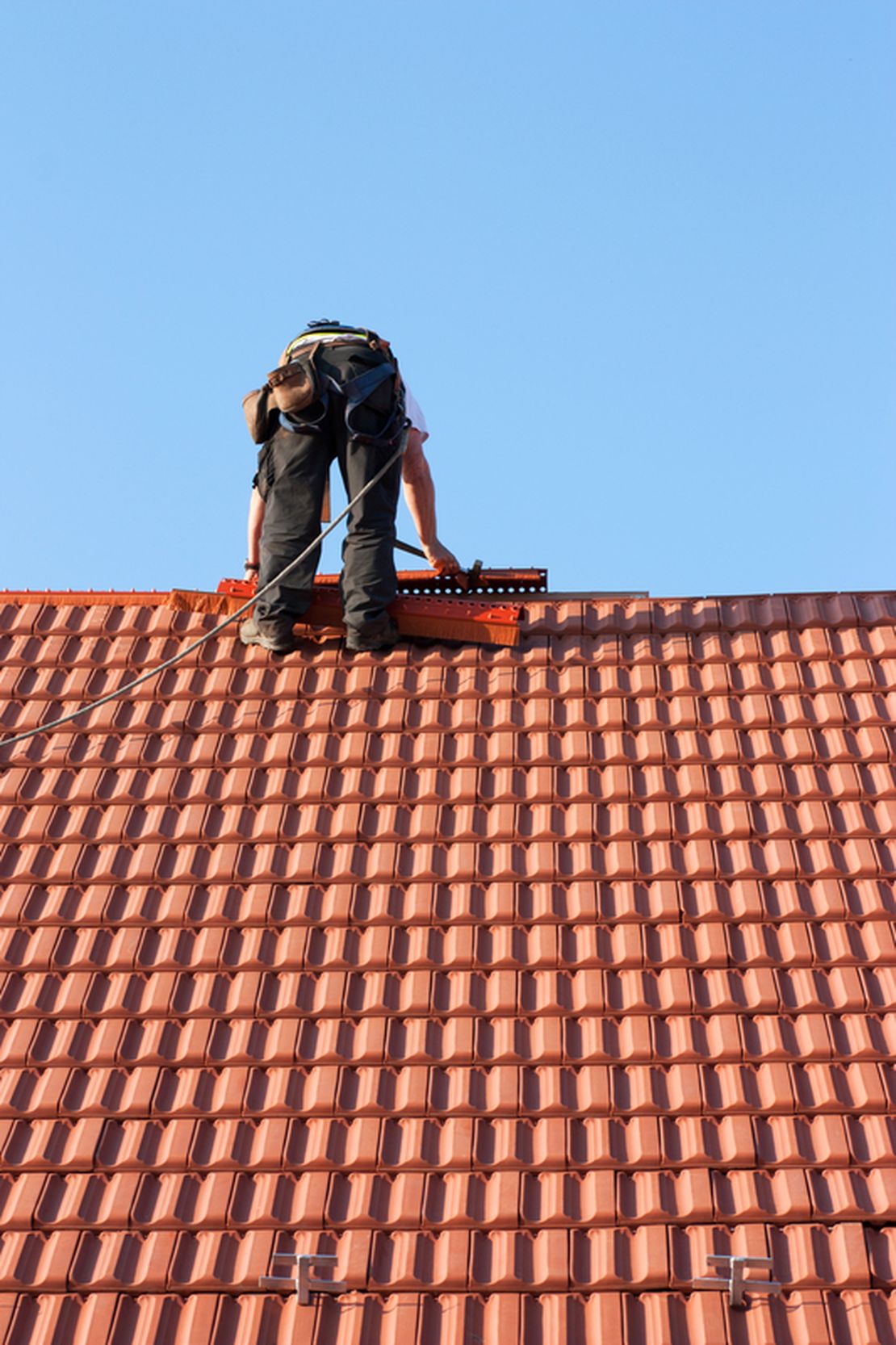 Roofing contractor repairing a tiled roof, tracked using Cinderblock job management software.