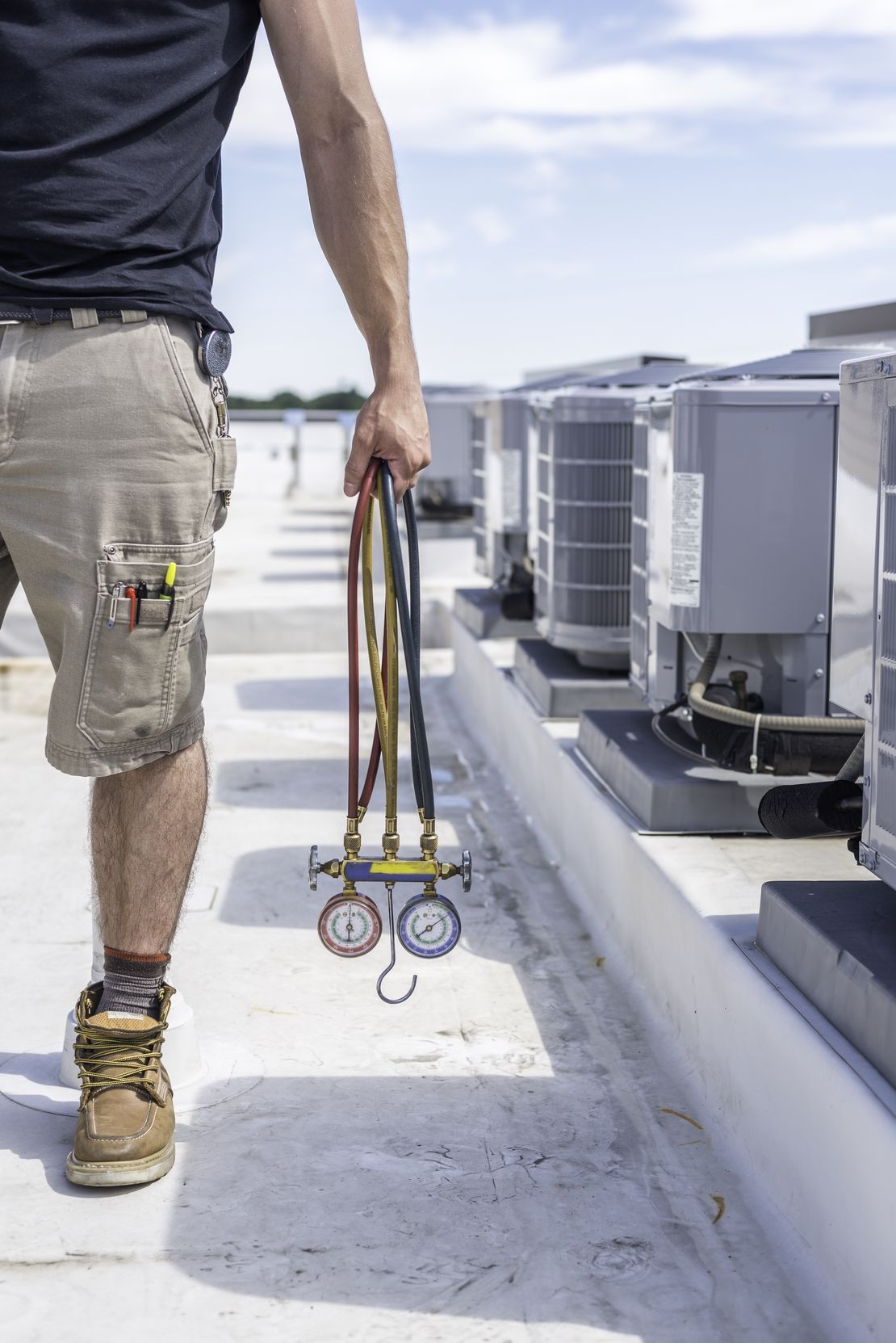 HVAC technician inspecting a rooftop AC unit while managing the job with Cinderblock job management software.