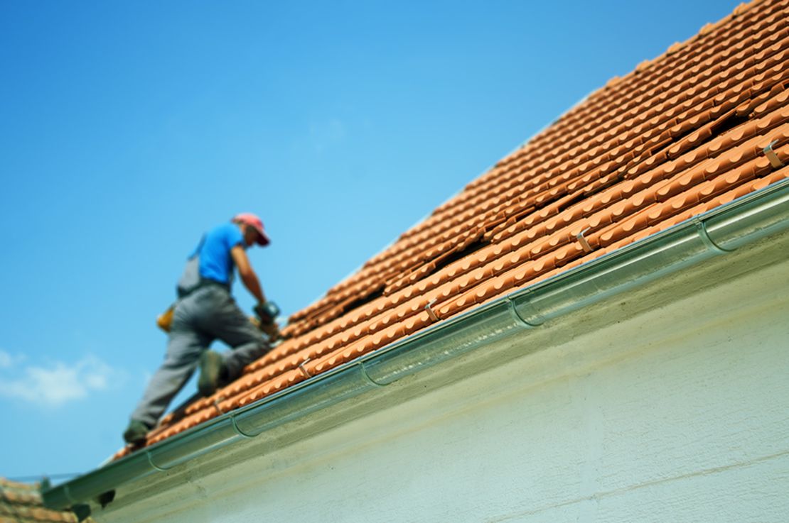 Roofing contractor repairing a tiled roof, tracked using Cinderblock job management software.